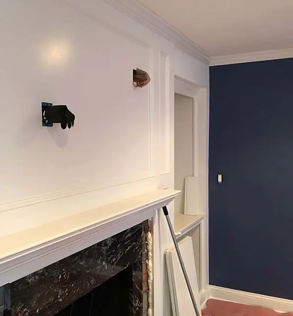 Navy, charcoal, and white millwork — Mantel, panel molding, navy wall